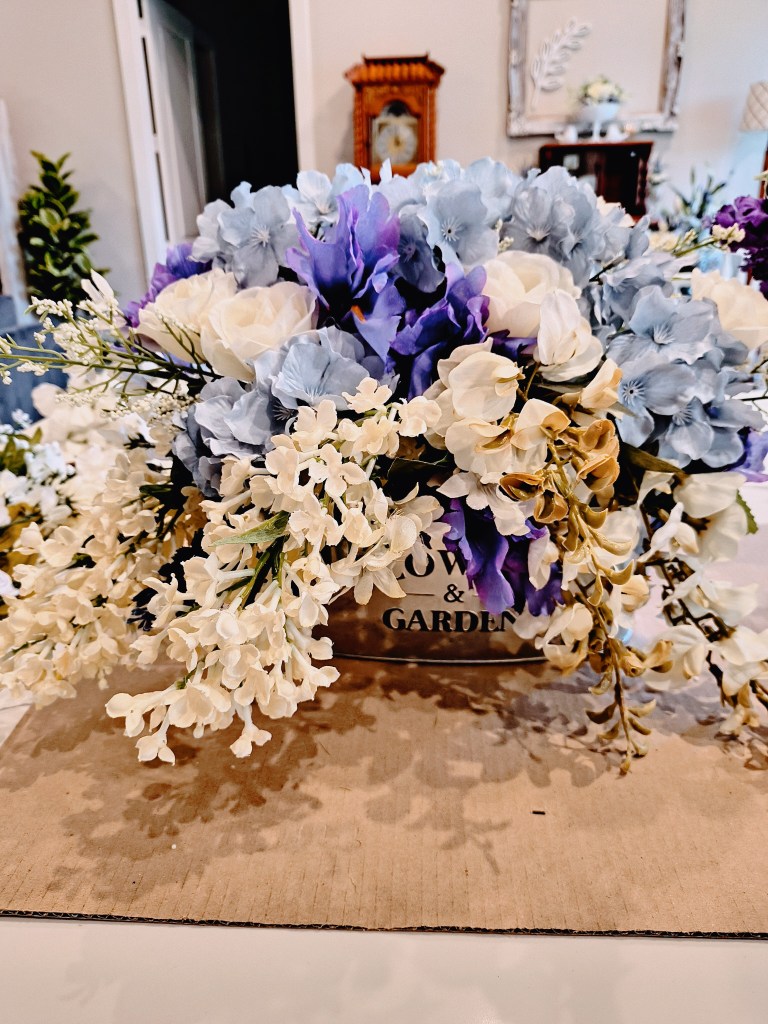 Faux floral arrangement in white, blue and purple.
acrossthelake.blog