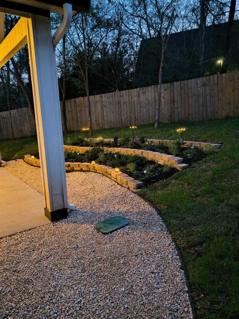 3 tiered backyard garden on hillside lit up at night.  acrossthelake.blog