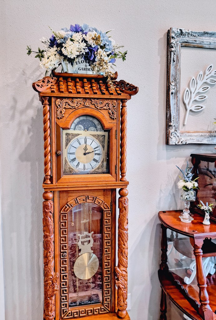 Faux floral arrangement atop a grandfather clock.
acrossthelake.blog