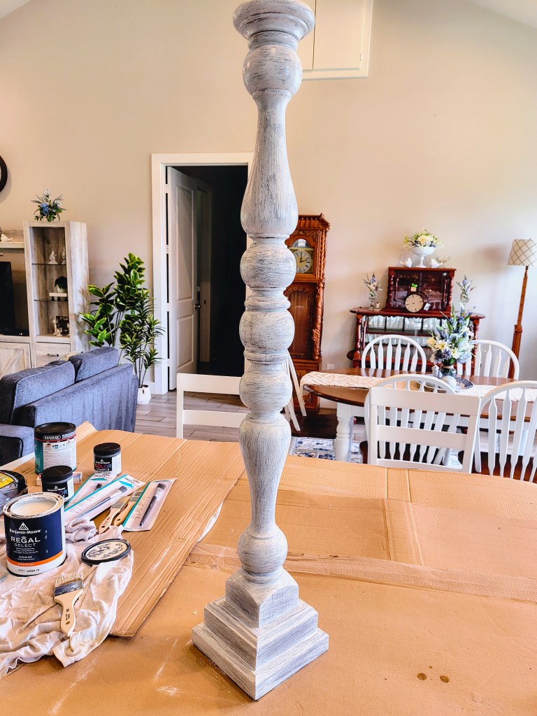 DIY Paint Project:  Tall wooden candlestick holder transformation from burgundy to white.  First coat of white.
acrossthelake.blog