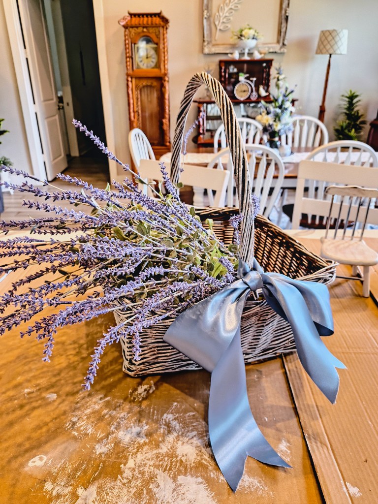 White washed wicker basket filled with faux lavender and tied with a dusty blue satin ribbon bow.
acrossthelake.blog 